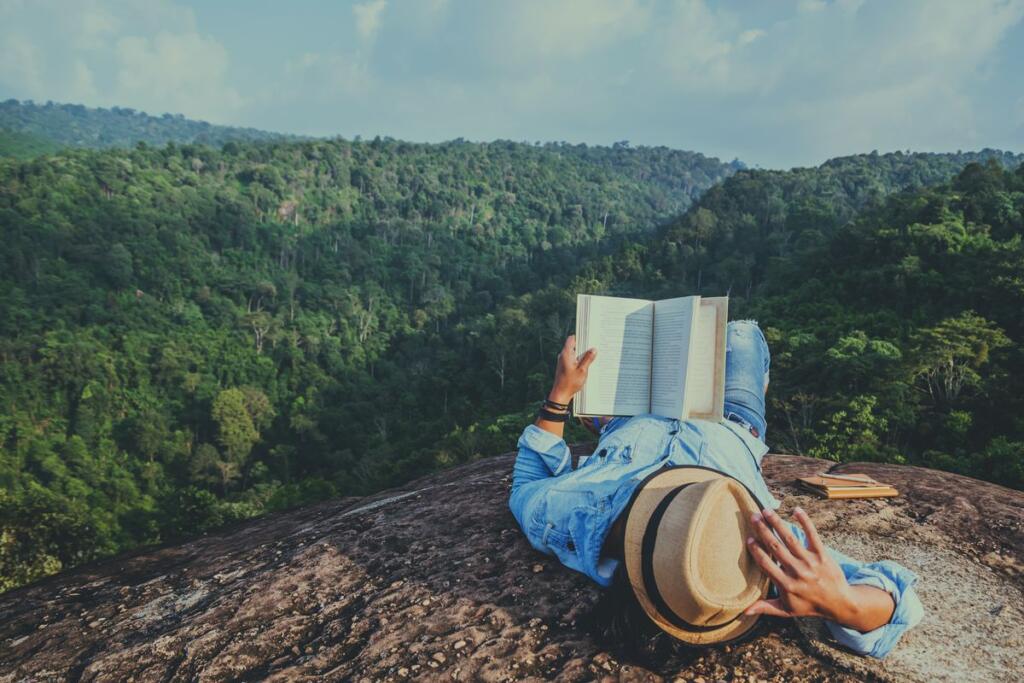 Uomo legge un libro in montagna