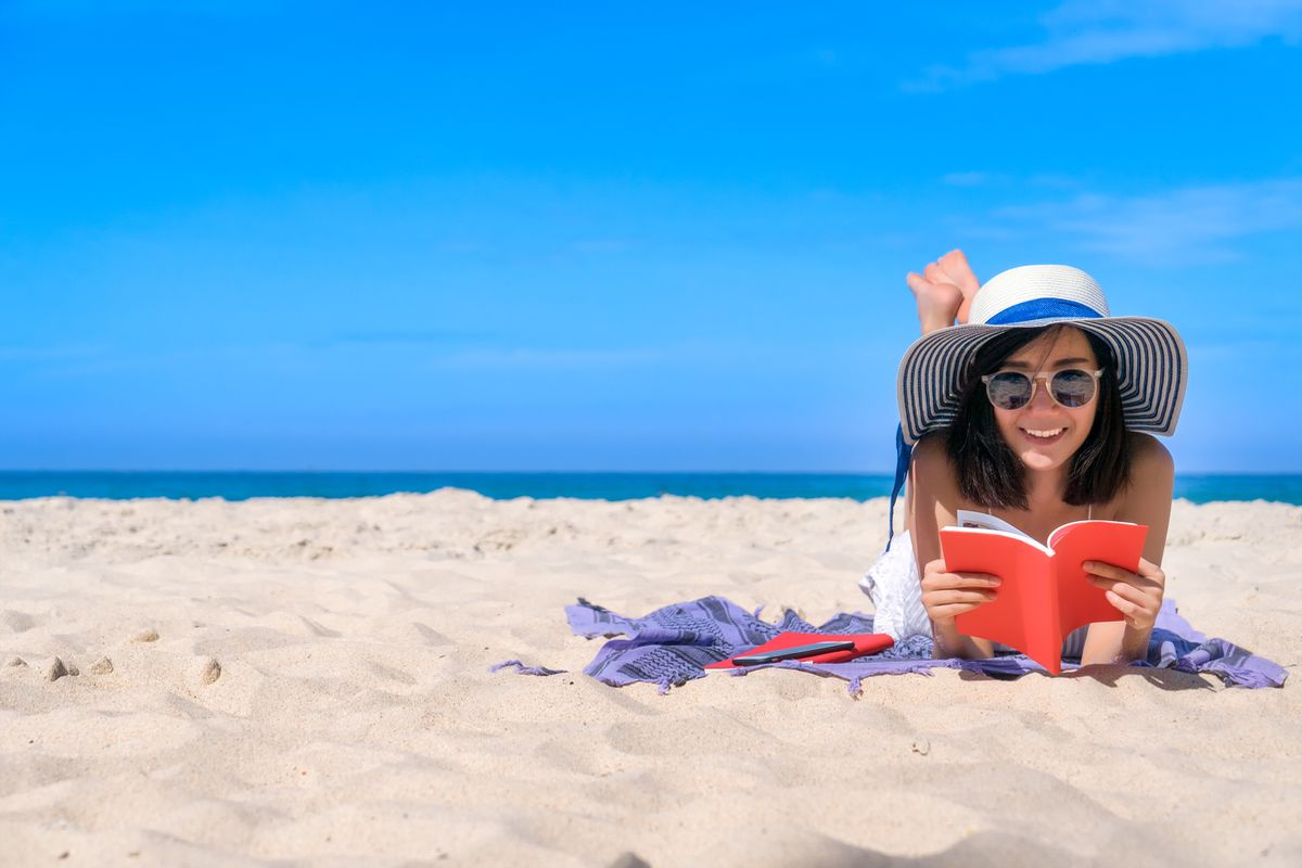 Ragazza legge libro in spiaggia