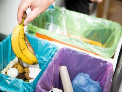 Una donna mette una buccia di banana nel bidone dell'umido
