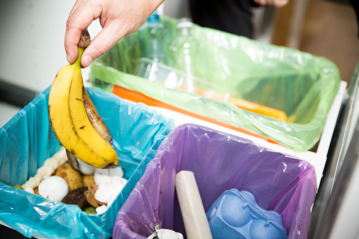 Una donna mette una buccia di banana nel bidone dell'umido