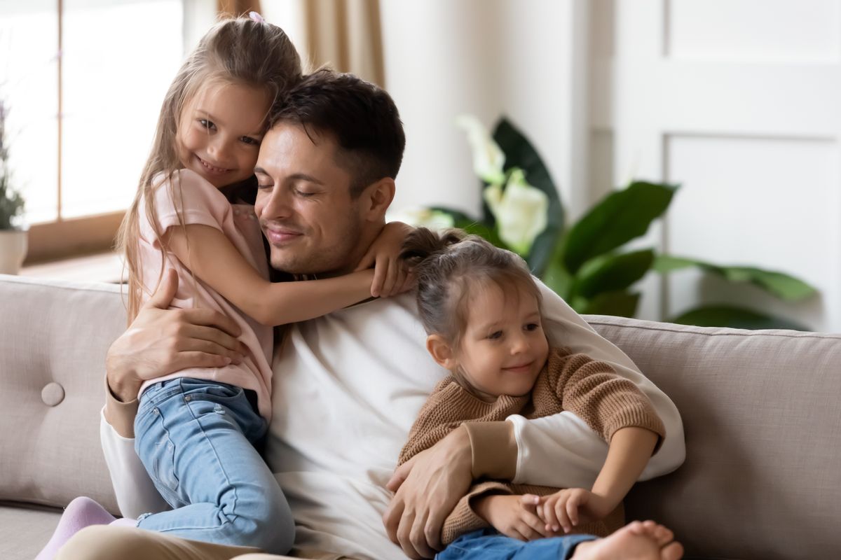 padre e figlie casa divano abbracci