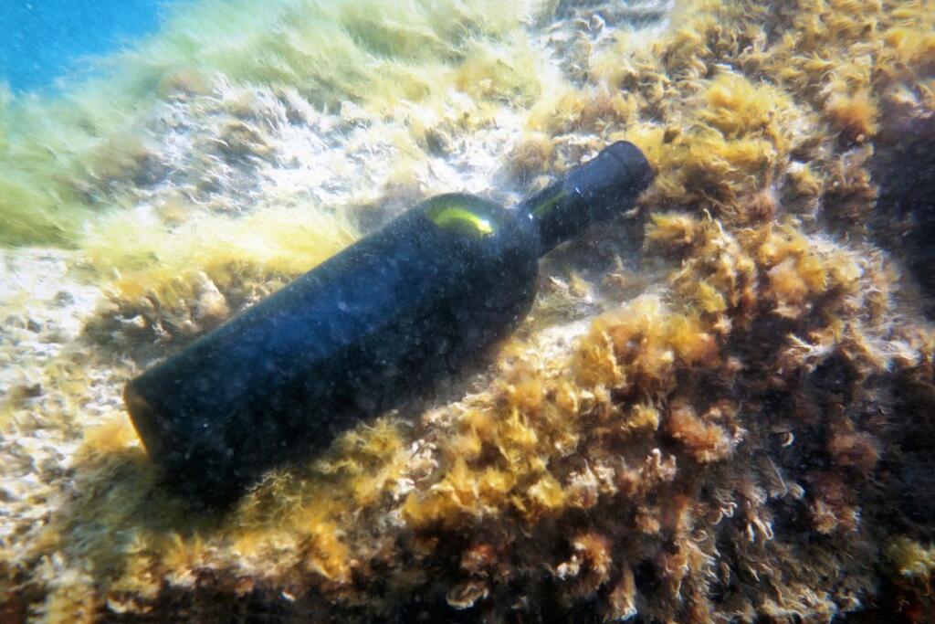 Una bottiglia di vino affinata su un fondale marino