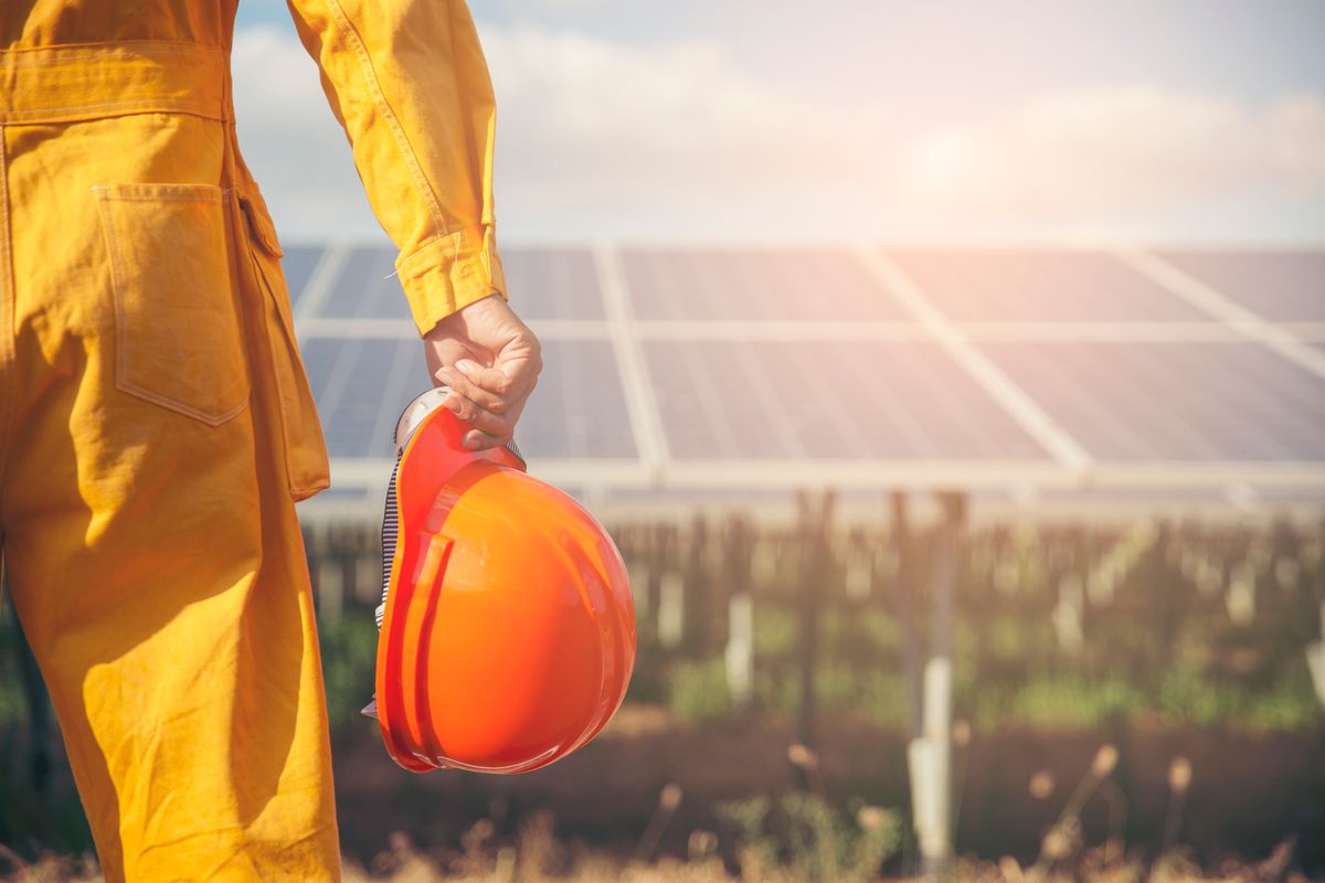 Un operatore tiene il casco di sicurezza arancione al termine dei lavori su pannelli solari