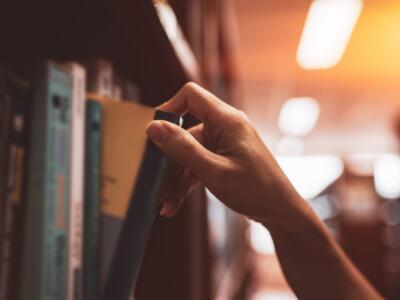 Una donna prende un libro dallo scaffale di una biblioteca