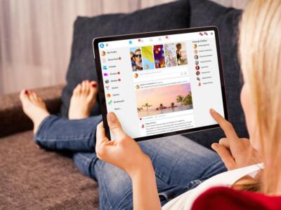 Una utente sul divano naviga su Facebook