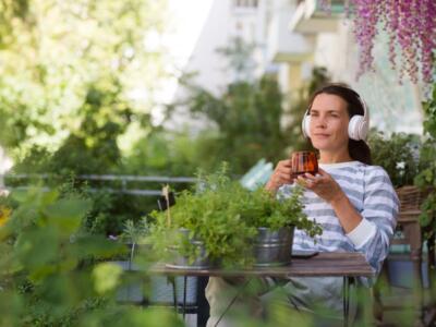 Donna che beve una tisana e ascolta musica in giardino