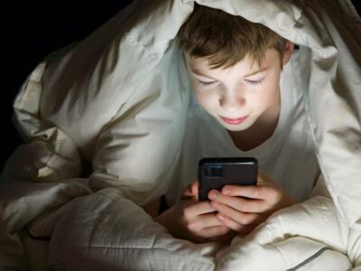 Bambino con smartphone a letto