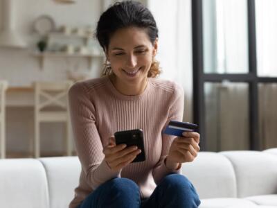 Una cliente con carta controlla il conto corrente su smartphone
