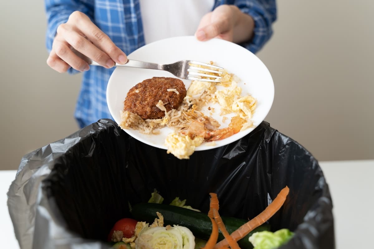 Un uomo spreca cibo buttando i resti di un pasto