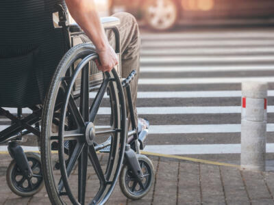 Un uomo disabile in sedia a rotelle attraversa sulle strisce pedonali