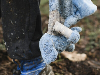 Un bambino tiene in mano un pupazzo durante i bombardamenti