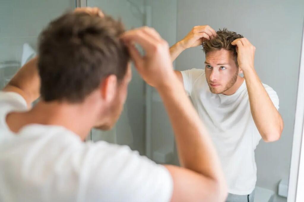 Uomo allo specchio si sistema i capelli