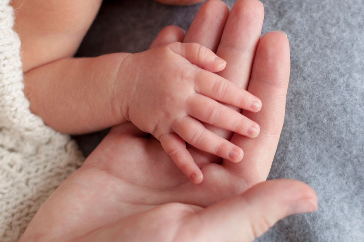 Una mamma tiene la mano del suo neonato