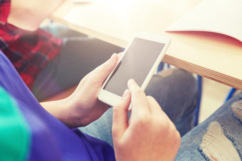 Un ragazzo in classe a scuola con lo smartphone