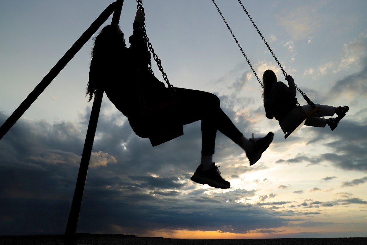 Due ragazze su un'altalena al tramonto