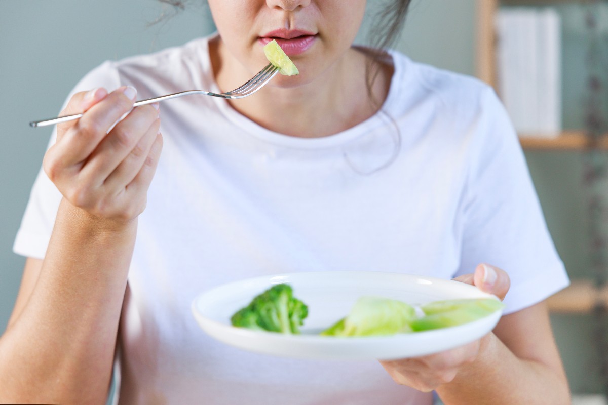 Una ragazza mangia verdure e insalata