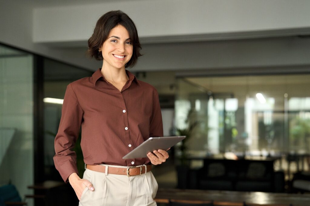 Donna sorridente in ufficio con tablet in mano