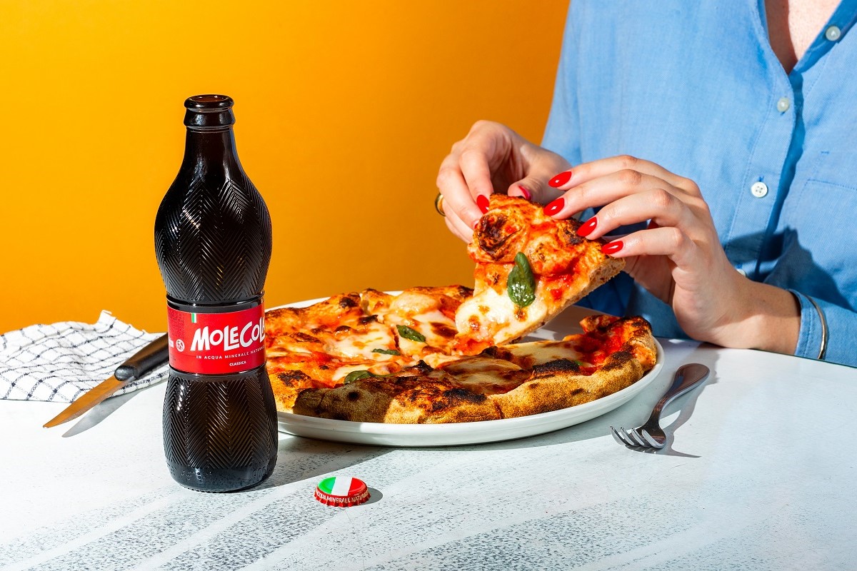 Una donna mangia una pizza bevendo una Molecola