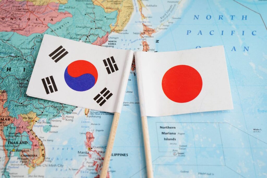 Bandiere di Corea del Sud e Giappone su sfondo con mappa geografica.