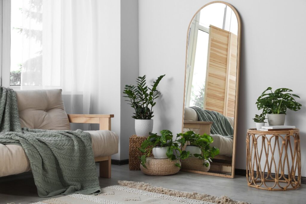 Living con ampio specchio, divano e piante