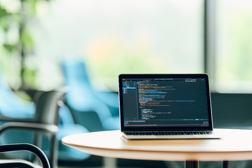 Computer Mac su scrivania con software di programmazione aperto sullo schermo.