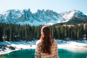 Donna che ammira un paesaggio con lago e montagne innevate